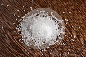 Heap crystals of sea salt or coarse salt on wooden background