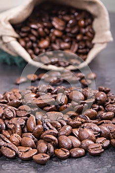 Heap of dark roasted fragrant coffee beans in jute bag