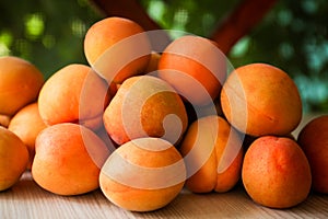 Heap of delicious ripe apricots on wooden table outdoors, closeup