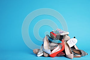 Heap of different shoes on color background