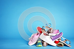 Heap of different shoes on color background