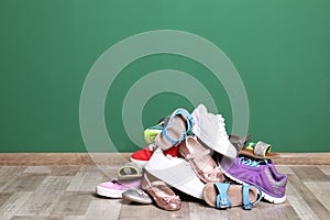 Heap of different shoes on floor against color wall