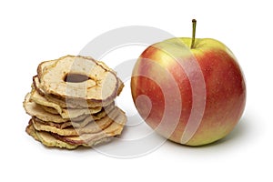 Heap of dried apple chips and a fresh Elstar apple on white background