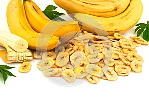 Heap of dried banana chips with yellow banana bunch and green leaves