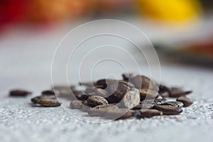 A heap of dried black watermelon seeds close-up on a white table background. planting season. close up top view copy space