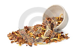 Heap of dried fruit tea infusion with oranges and strawberries mixed with tea leaves and herbs in tea bowl over white background
