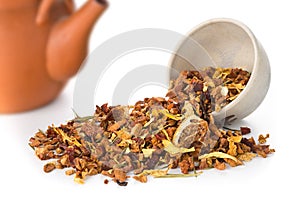 Heap of dried fruit tea infusion with oranges and strawberries mixed with tea leaves and herbs in tea bowl over white background