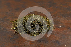 Heap of dried green tea leaves on grey table, closeup