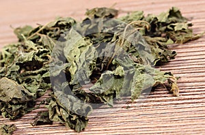 Heap of dried nettle on wooden surface photo