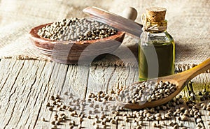 Heap of dried organic hemp seeds or cannabis plant seeds in spoon and bowl with glass of hemp seed oil