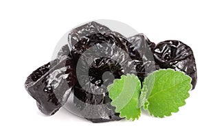 Heap of dried plums or prunes with a mint leaf on white background