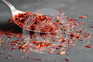 Heap of dried saffron spice in spoon on dark rustic background