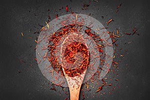 Heap of dried saffron spice in spoon on dark rustic background