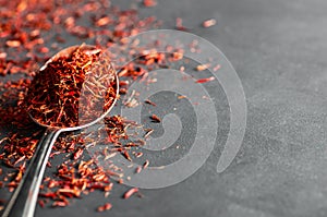 Heap of dried saffron spice in spoon on dark rustic background