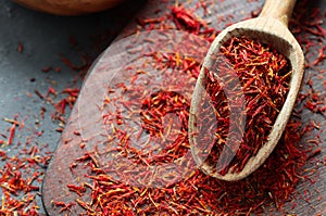 Heap of dried saffron spice in spoon on rustic background