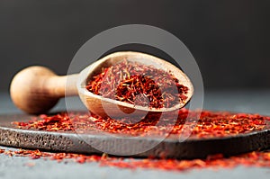 Heap of dried saffron spice in spoon on rustic background