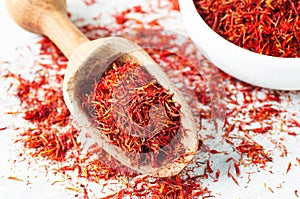 Heap of dried saffron spice in spoon on rustic background