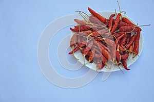 Heap of dry red chilli peppers on the white plate isolated over white background with copy space