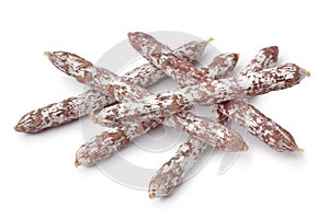 Heap of dry smoked salami sticks close up for a snack on white background