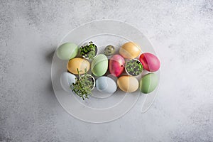 Heap of dyed multi-colored eggs and green sprouts in egg shell  on concrete background. Top view, copy space. Food background.