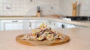 Heap of farfalle arcobaleno rainbow bowties pasta on the plate. Rotating camera with white kitchen on the background. Dolly-shot