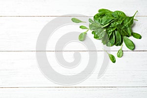 Heap of fresh green healthy spinach on white wooden table, top view. Space for text