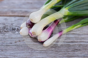 Heap of fresh, green and red onion on the wooden background close up.