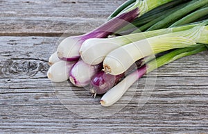 Heap of fresh, green and red onion on the wooden background close up.