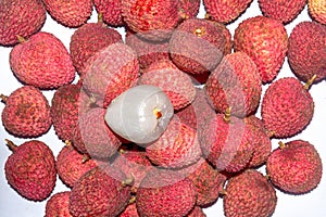 A heap of fresh Lychee with a peeled Lychee on top