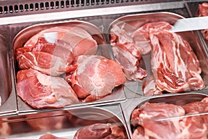 Heap of fresh meat food meat food background in supermarket store. Different types of raw meat in plastic boxes, leg of