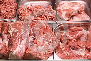 Heap of fresh meat food meat food background in supermarket store. Different types of raw meat in plastic boxes, leg of