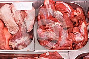 Heap of fresh meat food meat food background in supermarket store. Different types of raw meat in plastic boxes, leg of