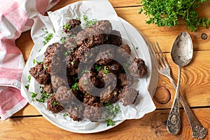 Heap of fresh pan fried beef meatballs on a plate on wooden table photo