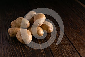 Heap of fresh potatoes on rustic wooden surface. Organic food, carbs, tubers.