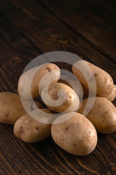 Heap of fresh potatoes on rustic wooden surface. Organic food, carbs, tubers.