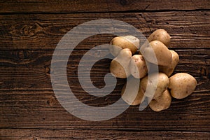 Heap of fresh potatoes on rustic wooden surface. Organic food, carbs, tubers.