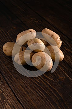 Heap of fresh potatoes on rustic wooden surface. Organic food, carbs, tubers.