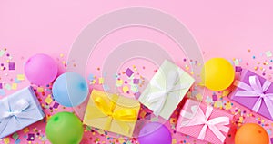 Heap of gift or present boxes, colorful balloons and confetti on pink pastel table top view. Birthday party background. Banner