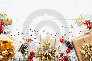 Heap of gifts or presents boxes, snowy fir tree and Christmas decorations on white wooden table top view. Flat lay.