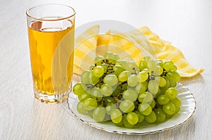 Heap of grapes in plate, napkin, glass of grape juice