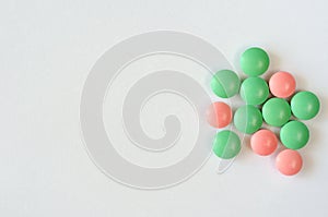 Heap of green and pink pills on a white background. Closeup of medicines. Copy space. Top view