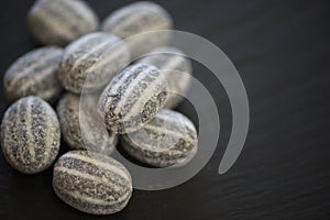 Macro food photography of sugar candy humbug sweets in black and white stripe patterns with peppermint flavor on black background