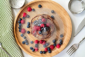 A heap of healthy vegan gluten free whole grain pancakes made with buckwheat flour topped with raspberries and blueberries