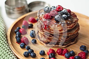 A heap of healthy vegan gluten free whole grain pancakes made with buckwheat flour topped with raspberries and blueberries