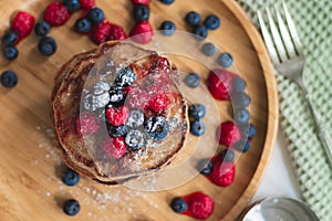 A heap of healthy vegan gluten free whole grain pancakes made with buckwheat flour topped with raspberries and blueberries