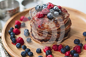 A heap of healthy vegan gluten free whole grain pancakes made with buckwheat flour topped with raspberries and blueberries