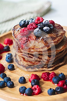 A heap of healthy vegan gluten free whole grain pancakes made with buckwheat flour topped with raspberries and blueberries