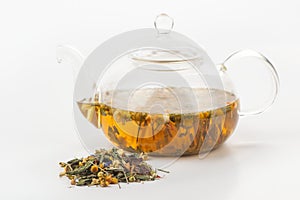 A heap of herbal tea and a glass teapot with brewing tisane