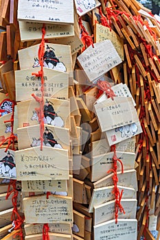 Heap of hung wooden shinto Ema plaques depicting the guardian spirit Sugawara no Michizane.