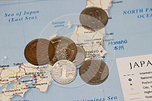 Heap of Japanese Yen coin money put on the Japan map. Concept of finance or travel